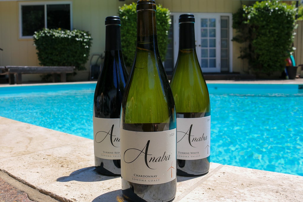 The three bottles of wine included in the three pack in the foreground with a swimming pool in the background.