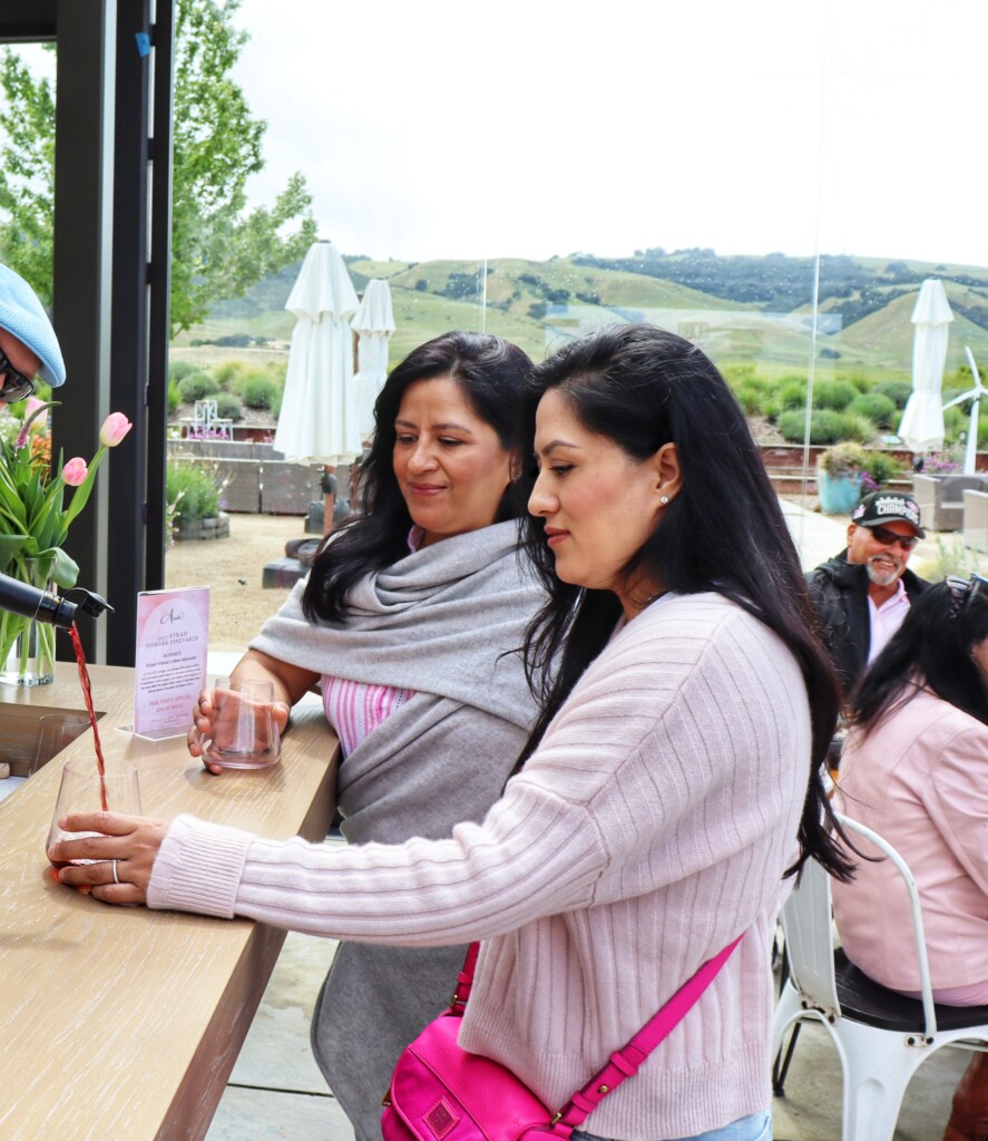 Red wine being poured for two guests on a patio