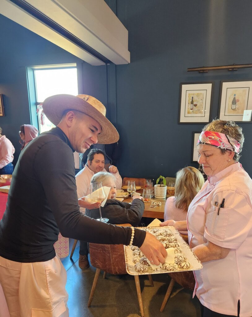 Chef serving a guest from a tray of chocolate spice cookies